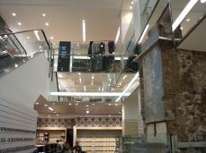 Glass balustrade with stainless steel handrails and flashing around escalator and old city wall.